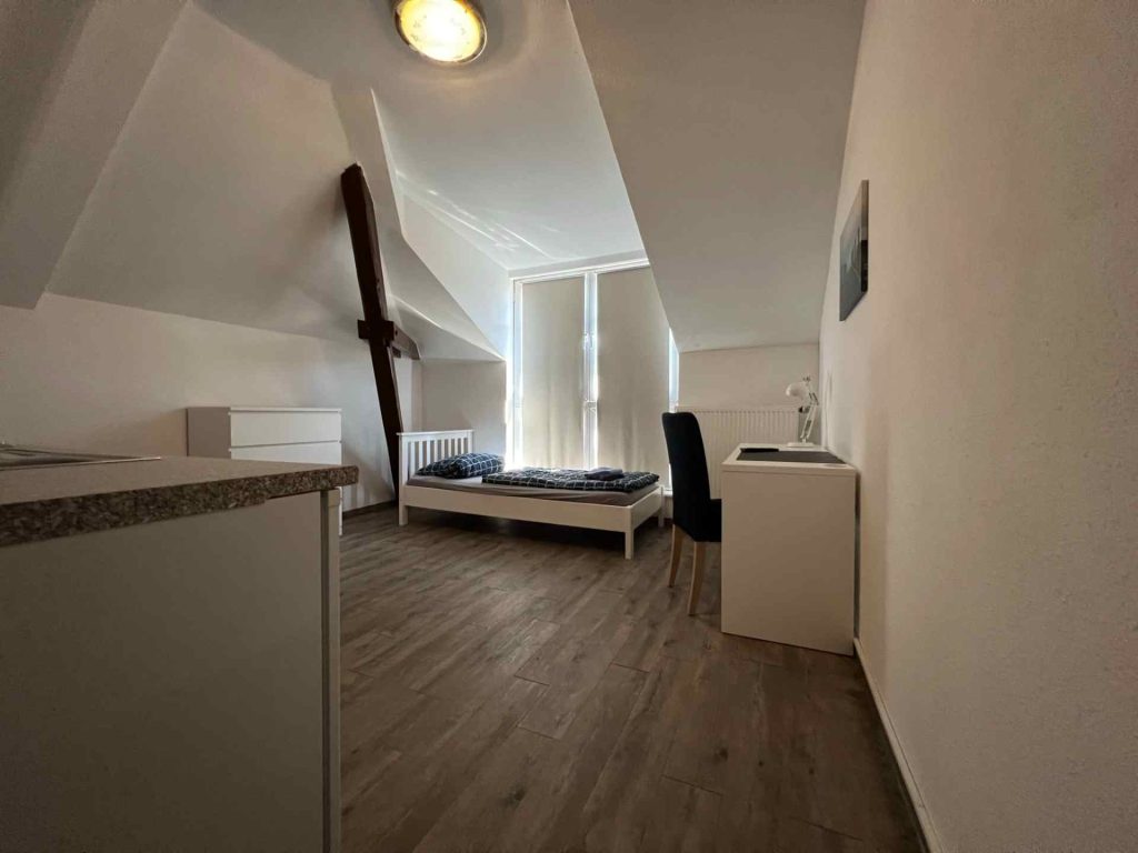 Dachzimmer mit Bett und Schreibtisch